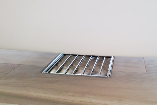 Stainless steel floor grate installed beneath the Oasis Hammock Bath for discreet and efficient drainage.